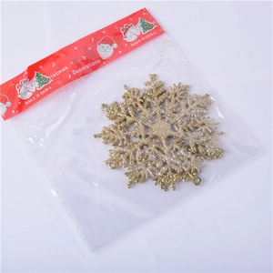 Close-up of golden glitter acrylic snowflake ornament in Christmas themed packaging