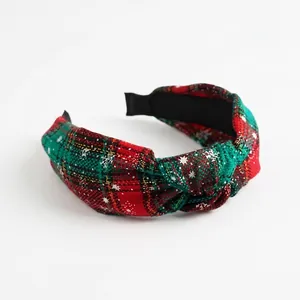 Detail of red and green plaid Christmas headband with white snowflake prints and top knot