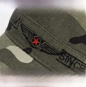 Detail of army green camouflage flat top hat featuring red star and wing embroidery