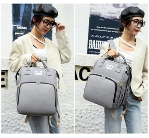 Detail of grey canvas diaper backpack with front zipper pocket and stylish printed label