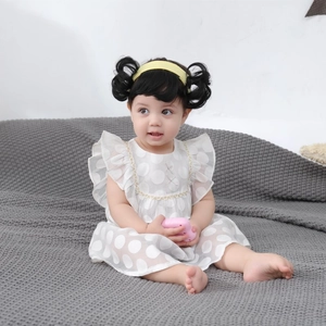 Detail of baby white polka dot dress with ruffle sleeves and matching yellow headband