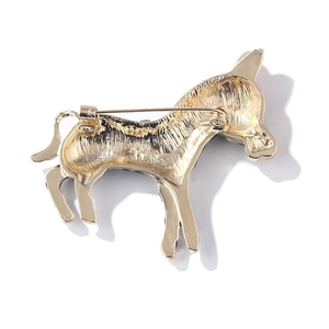 Macro detail of golden metal donkey brooch showing the secure pin fastener and texture
