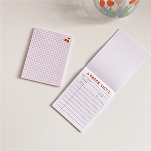 Close-up of pink cherry grid notepad and paper check list for daily planning