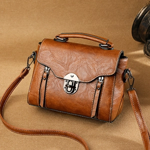 Vintage brown crossbody handbag with top handle and metal lock on textured background