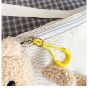 Macro shot of canvas material with plush bear charm and vibrant yellow zipper detail