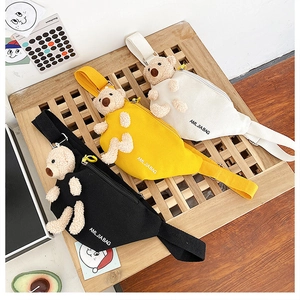 Detailed view of canvas chest bags in black, yellow, and white with cute plush bear decor