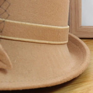Détail macro du chapeau en feutre camel avec ruban élégant et voile en résille noire