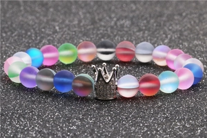 Detail of silver crown charm on a frosted iridescent beaded bracelet with rainbow glow