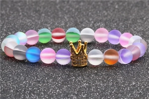 Macro shot of colorful matte aurora beads and a gold crown charm with zircon inlay