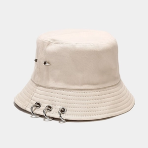 Détail des anneaux argentés et clous punk sur un chapeau bob en toile beige