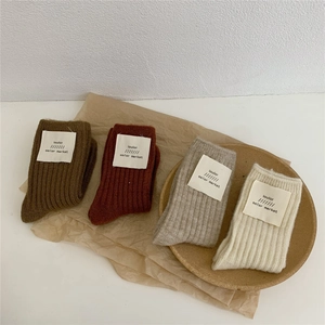 Detailed macro view of four pairs of ribbed wool socks in brown, red, beige, and cream colors