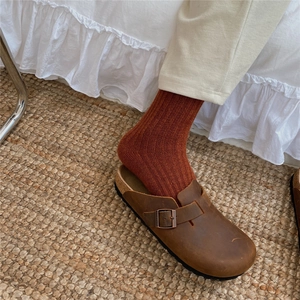 Close-up of rust red ribbed wool socks worn with brown leather cork buckle clogs