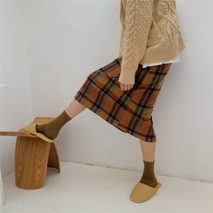 Close-up of thick brown wool socks styled with a plaid skirt and cozy yellow loafers