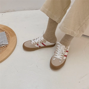 Detail of beige wool socks with red and white stripes worn with casual canvas shoes