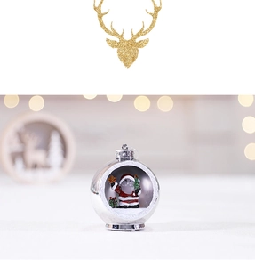 Detail of a glowing silver Christmas ball ornament with a Santa Claus and tree scene