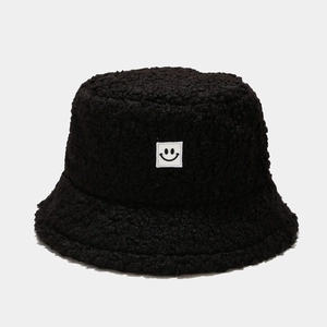 Close-up of black teddy fleece fabric texture and smiley face patch on bucket hat