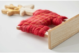 Close-up of wooden reindeer ornament with red wool texture and gold thread grid detail