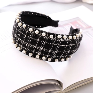 Detail of black tweed headband with white pearls on a minimalist open magazine