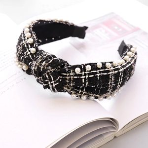 Detailansicht eines schwarz-weißen Tweed-Knoten-Haarreifs mit eleganten Perlenverzierungen