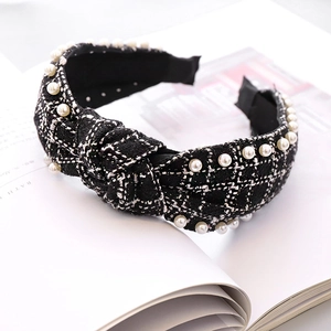 Close-up of a tweed knotted headband with pearl accents on a white magazine background