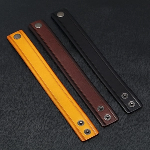 Detailed view of genuine leather bracelets in yellow, brown, and black with metal snaps