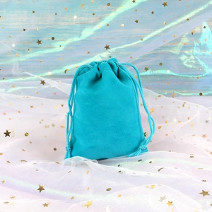 Detail of teal velvet drawstring jewelry pouch with soft texture on a dreamy backdrop