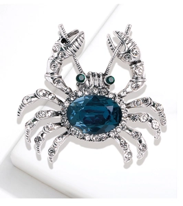 Detail of crab brooch with blue gemstone, green eyes and sparkling small crystals