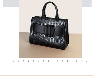 Detail of black leather handbag featuring embossed letters and a large decorative square buckle