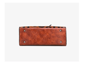 Detailed view of the brown leather bag base featuring protective silver metal feet studs