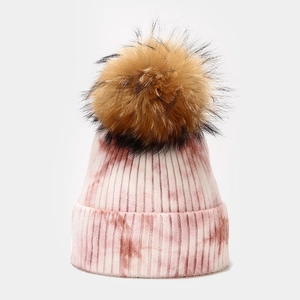 Detail of pink tie-dye knitted beanie with a large fluffy brown pompom and soft texture