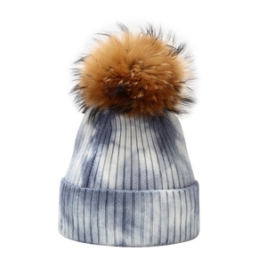 Women's tie-dye knit beanie with large raccoon fur pompom in blue and white colors