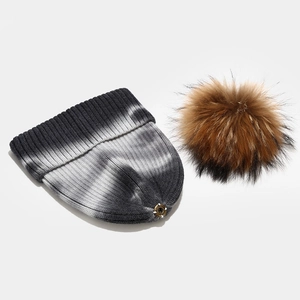 Detail of tie-dye knit beanie with detachable brown faux fur pom pom and snap button