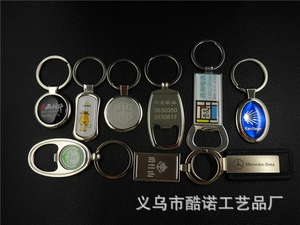Flat lay of multiple custom beech wood and metal keychains on a textured black surface