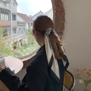 Classic black and white striped silk scarf used as an elegant hair accessory for women