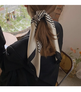 Detail showing classic black and white striped silk scarf styled as a hair accessory