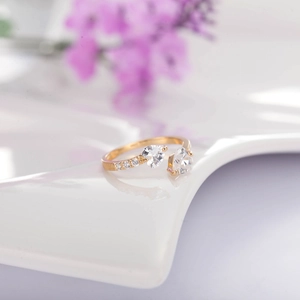 Elegant gold open ring featuring heart-shaped zircon stones on a white ceramic plate