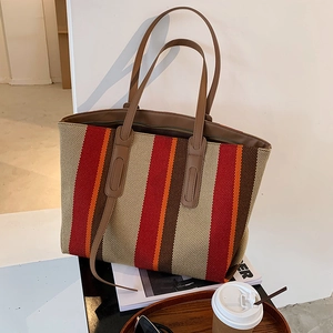 Détail du sac cabas en toile à rayures colorées avec anses en cuir sur un bureau stylé