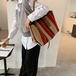 Grand sac cabas en toile à rayures porté par une femme dans un café élégant