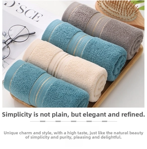Close-up of four soft cotton towels with gold stripes in a wooden tray home setting