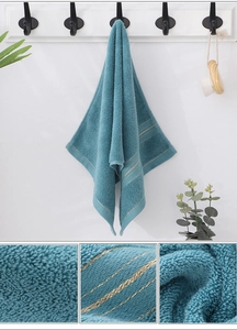 Detail of teal cotton face towel with gold stripe accents and soft looped texture