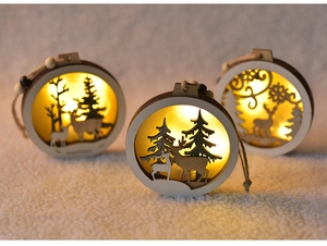 Close-up of wooden Christmas ornaments with warm LED lights on a white plush background