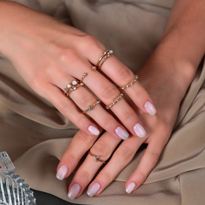 Detail of elegant gold moon and star rings worn on hands over a soft beige silk fabric