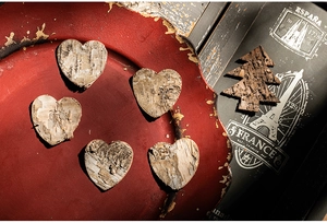 Artistic detail of wooden heart and Christmas tree bark ornaments on a red vintage tray