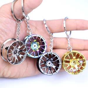Close-up of four metal car wheel rim keychains in silver, rainbow, gun grey, and gold