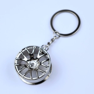 Close-up of a silver metal car wheel rim keychain with polished chrome finish