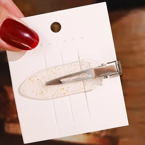 Detailansicht der transparenten Acryl-Haarspange mit eingearbeiteten goldenen Glitzerpartikeln