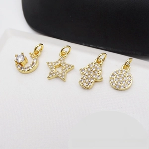 Macro view of gold-plated sun, moon, and Hamsa hand pendants with cubic zirconia