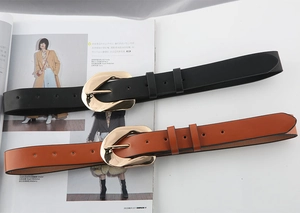 Detailed macro view of black and caramel brown leather belts with artistic golden buckles