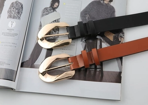 Detail of classic black and brown leather belts with polished gold curved buckles