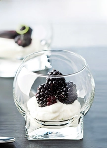 Macro shot of lead-free glass dessert bowl filled with fresh blackberries and cream